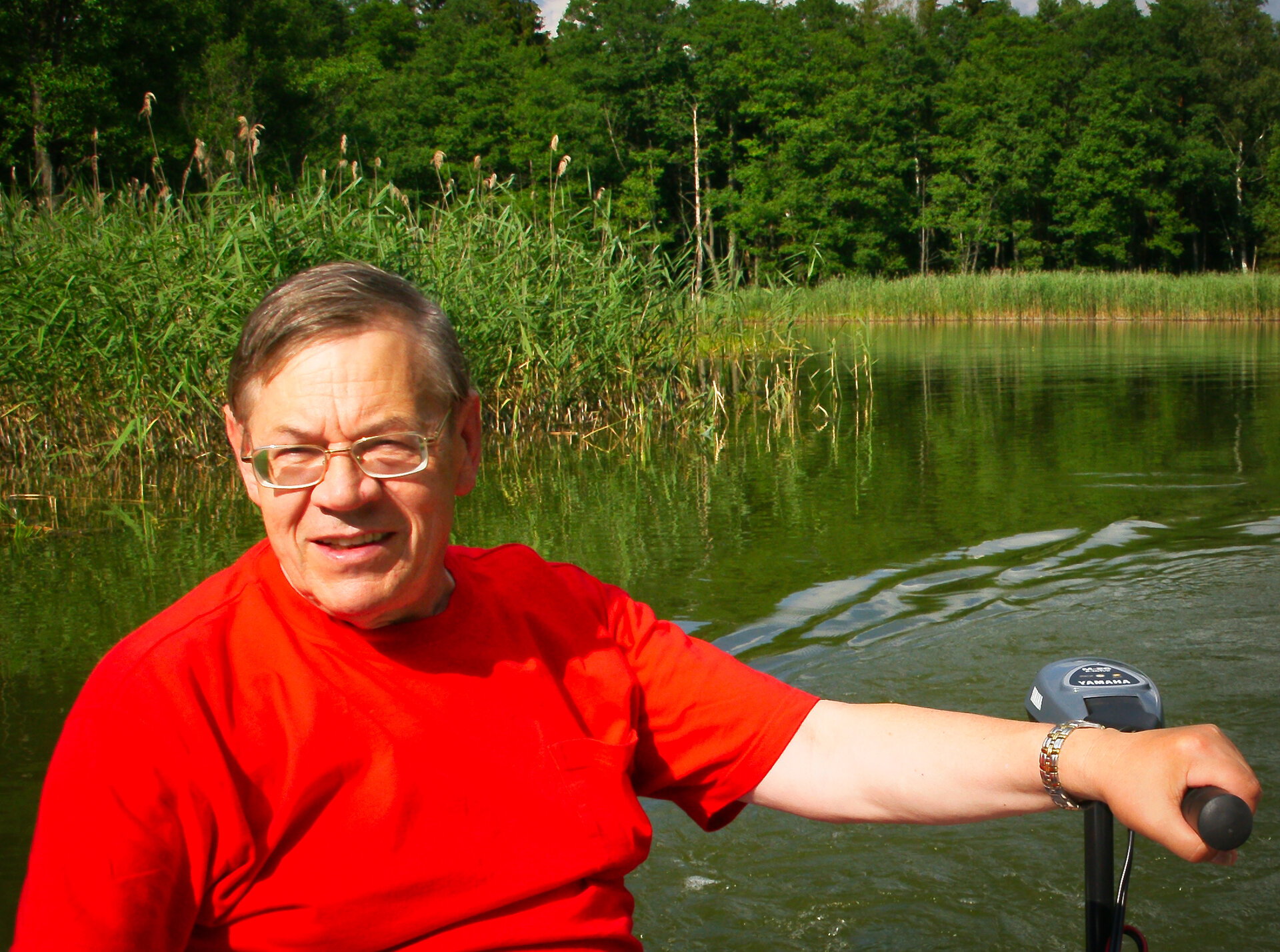 A biologist standing in a river, pumping water through a small filter to collect environmental DNA.